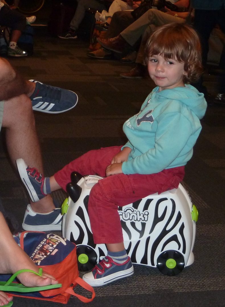 Robin sur sa valise zébre à roulettes