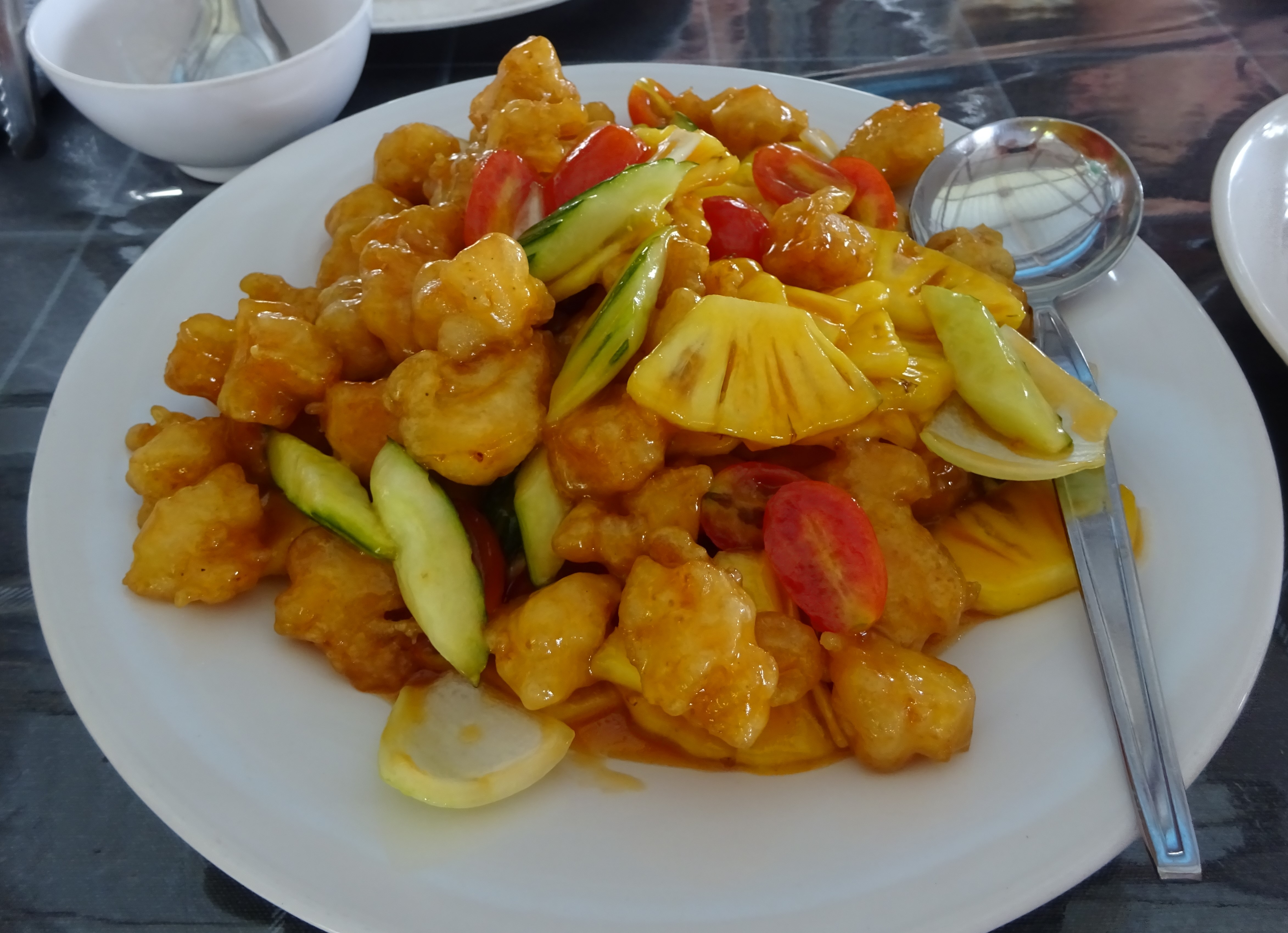 Poulet avec une sauce aigre-douce servi avec des morceaux d'ananas dans un restaurant sur pilotis lors de l'excursion à Phang Nha