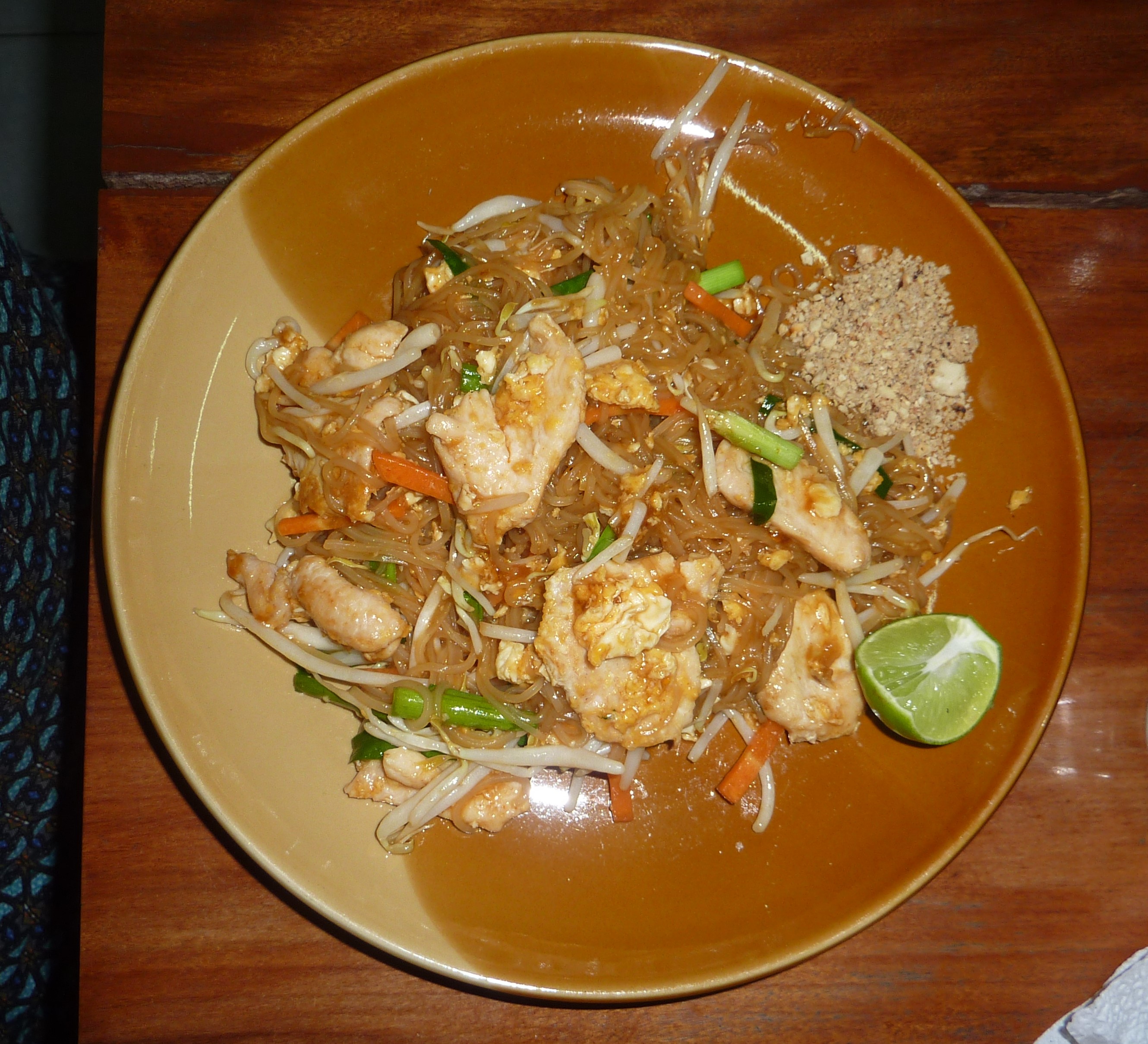 Pad Thaï traditionnel aux nouilles de riz avec poulet et légumes thaï parfumés + cacahuètes pilées et citron vert
